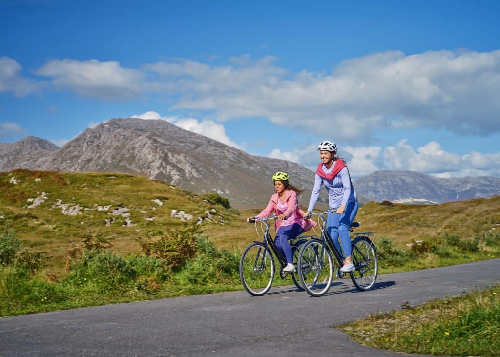 Two cyclists enjoying a sunny ride on a scenic mountain road.