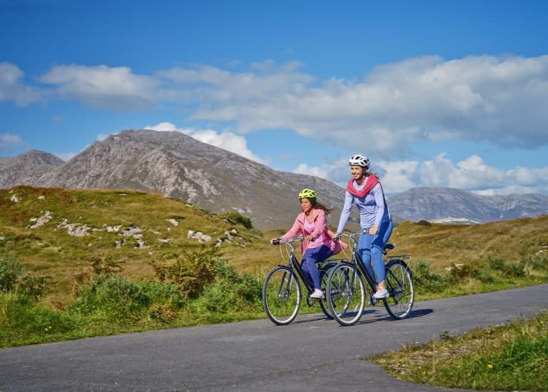 Two cyclists enjoying a sunny ride on a scenic mountain road.
