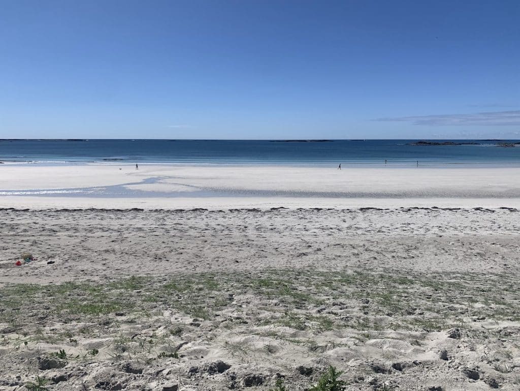 Sandy beach with calm blue sea and clear sky—discover Connemara’s tranquil beauty.