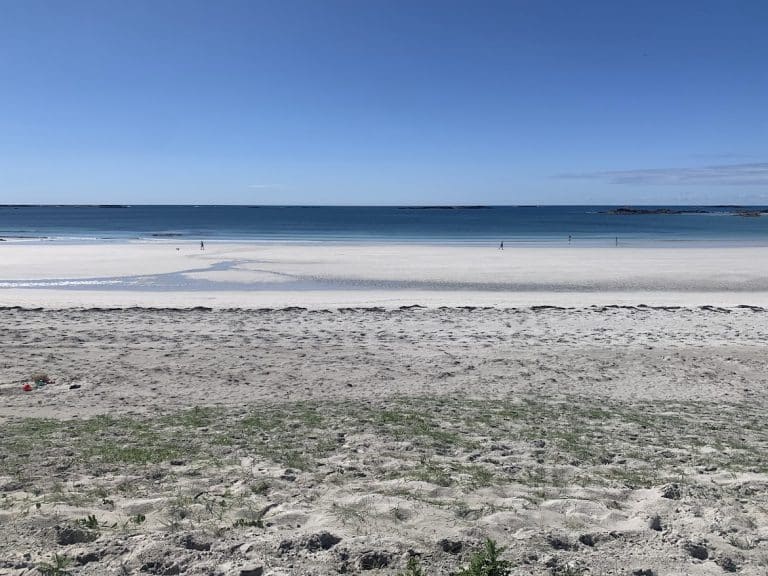 Sandy beach with calm blue sea and clear sky—discover Connemara’s tranquil beauty.