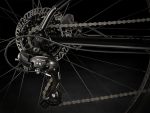 Close-up of Trek Marlin 5 - Cross Bar's rear derailleur, gears, chain, and disc brake.