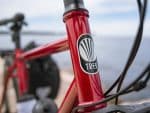 Close-up of a red Trek 520 Disc frame with black and white logo, near water.
