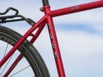 Close-up of a red Trek 520 Disc frame with rear wheel and rack, set against the sky.