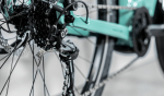 Close-up of an Allant+ 5 Lowstep Blue Sage bike’s rear derailleur, gears, and wheel spokes.