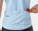 Hand placing a red snack bar into the back pocket of a Trek Solstice Women's Cycling Jersey.