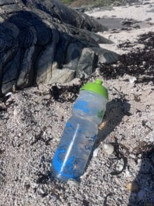 Clifden Bike Shop Water Bottle on sandy beach.