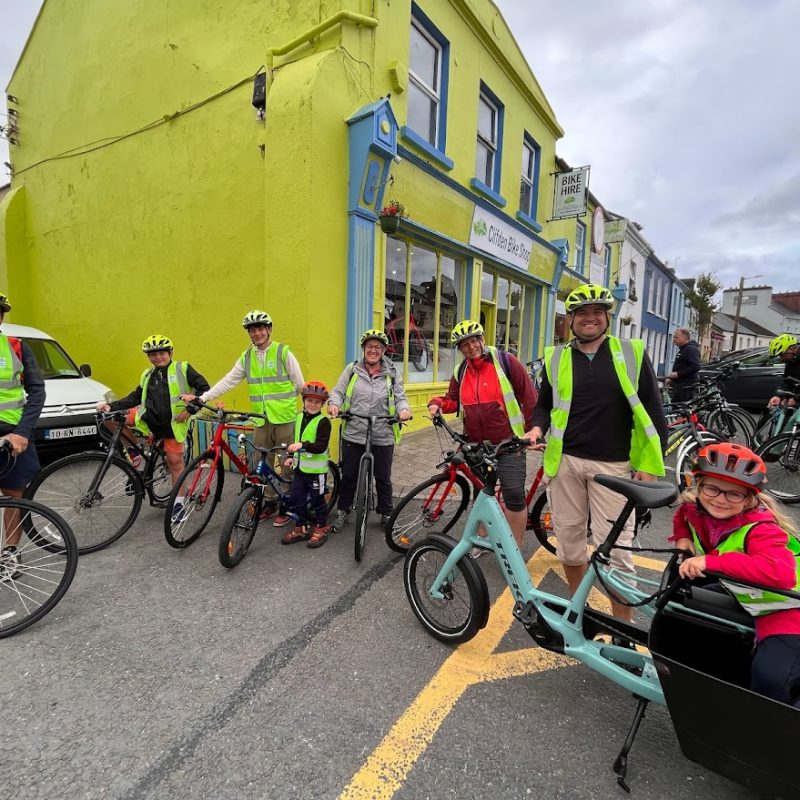 A group of cheerful cyclists with safety helmets and reflective jackets ready for a ride through the town.